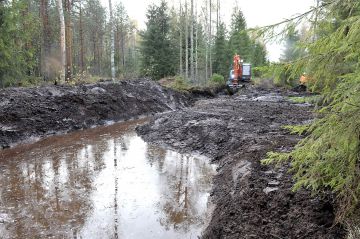 Kaivuri nostaa ja tasoittaa laskeutusaltaasta ja ojista kaivetun maan altaan ja ojien reunoille. (Kuvaaja: Juha Harju)