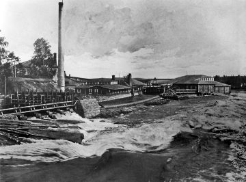 Tehdas kosken partaalla. Joesta saatiin vettä, sitä myöten uitettiin puut ja koski valjastettiin energiantuotantoon. Inkeroisten kartonkitehdas vuoden 1895 jäljennöskuvassa I. K. Inhan matkakirjasta Suomi kuvissa. Kuva: Stora EnsoSuomen Elinkeinoelämän Keskusarkisto Elka. (Kuvaaja: Stora EnsoSuomen Elinkeinoelämän Keskusarkisto Elka)