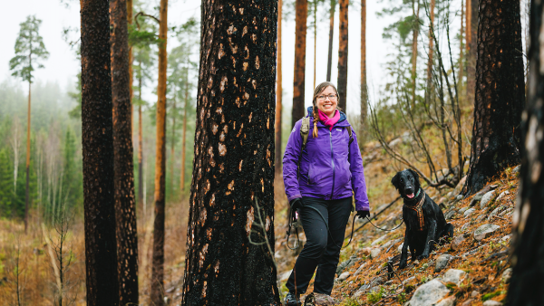 Sanna Ketola ja Hippu-koira ulkoilevat Evon metsäkoulun maastoissa, mutta ajatukset ovat usein omissa metsissä tasaisemmalla Pohjanmaalla. (Kuva: Seppo Samuli)